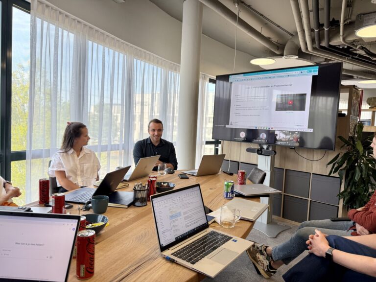 Deelnemers werken met laptops aan tafel tijdens een AI-workshop